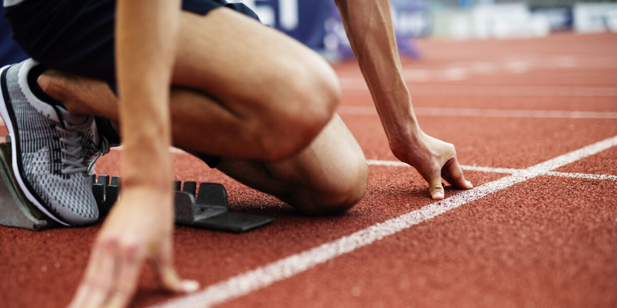 Unrecognizable Athlete Preparing For Start On Running Track.