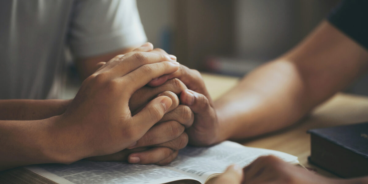 Christian group of people Holding hands together and praying on the holy bible. devotional for prayer meeting concept. praying worship to believe. Encouraging each other to get through the crisis.Love