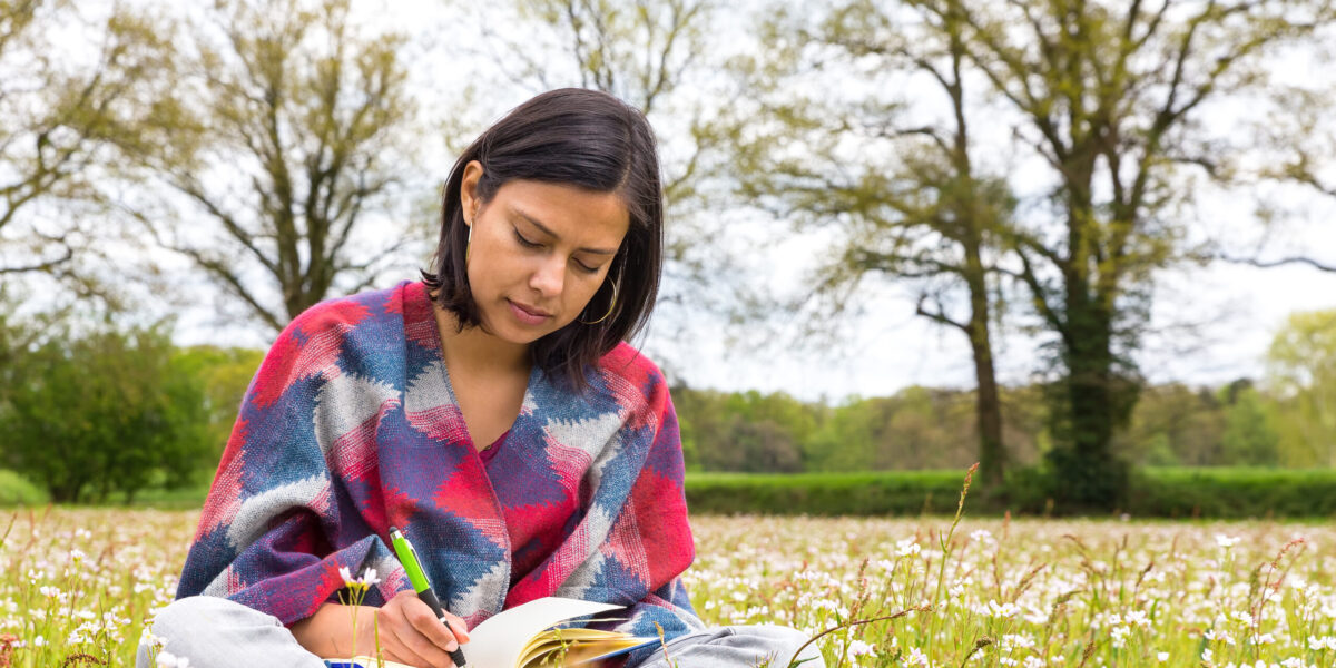 Woman writing in meadow with spring flowers