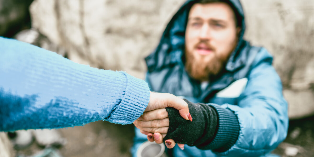 Homeless Male On The Street Getting Help From Female