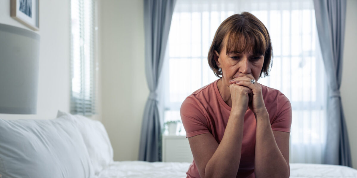 Caucasian mature woman frustrating while sit alone on bed in bedroom. Attractive old female upset depressed feel infuriating, sad and upset with life problem in house. Health care Medical Concept.