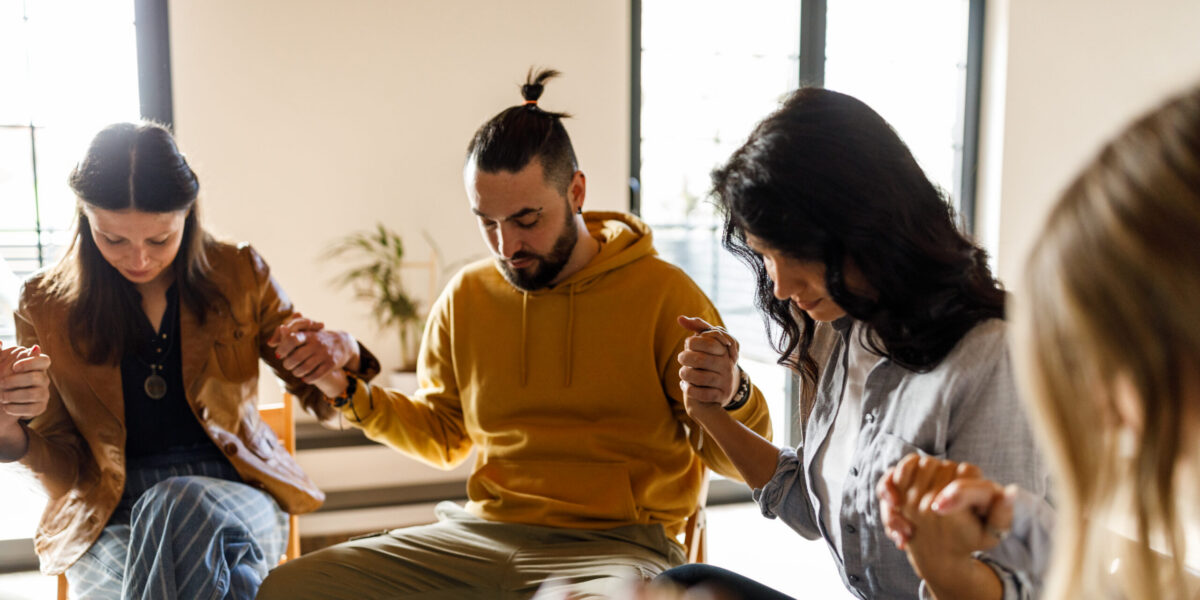 People in group therapy holding hands as a sign of support for one another