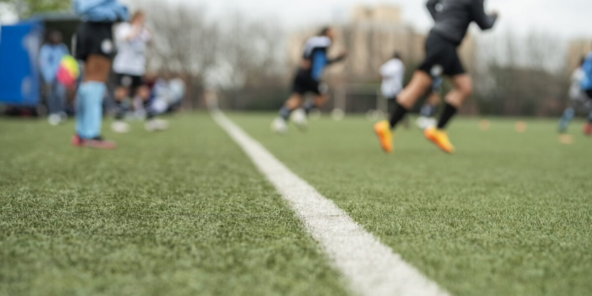 Young female soccer team running on the field from the sideline
