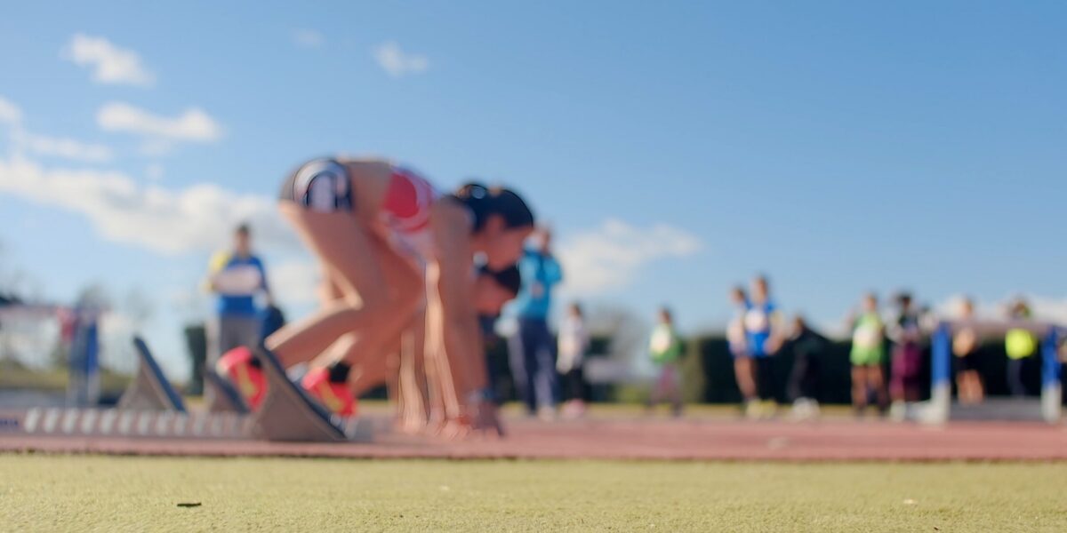 Sprinter in starting blocks on track and field, focused and ready for the race, representing determination, competition, and reaching goals at a sports event