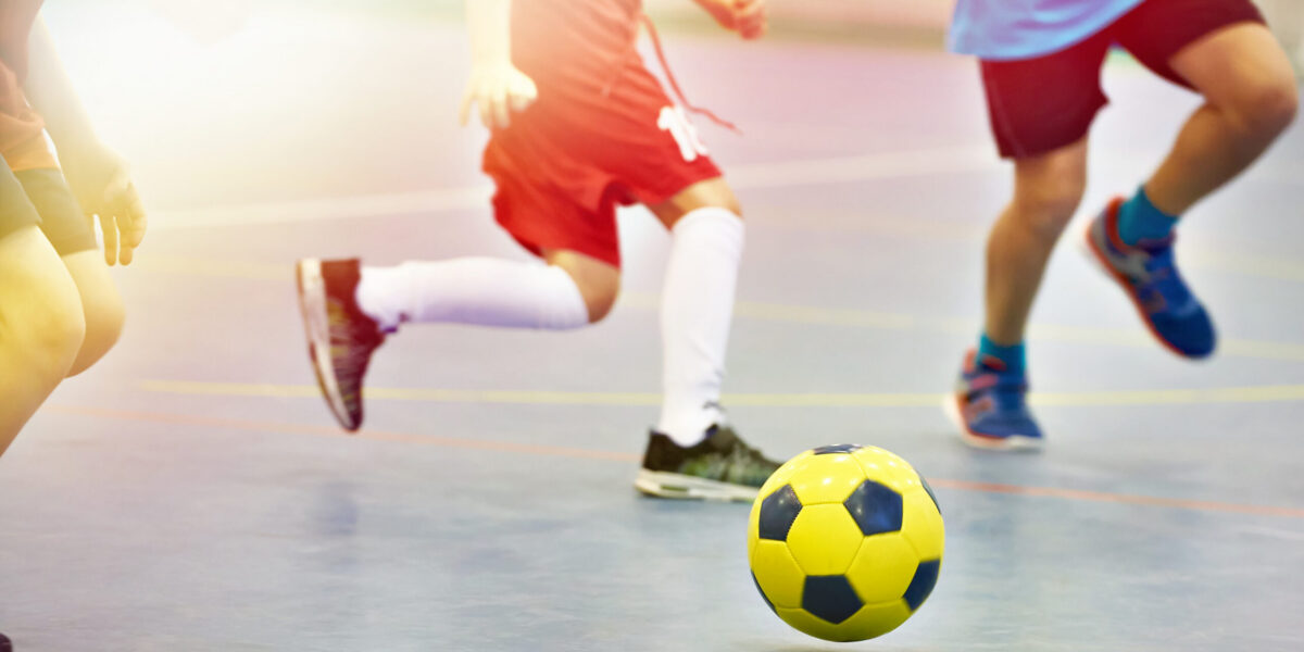 Children playing soccer indoors